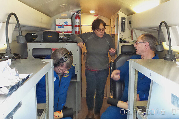 Picture of Amy Solomon and two crewmen on NOAA's Gulfstream, discuss dropsondes.