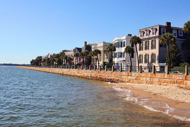 Water with historic homes behind a seawall