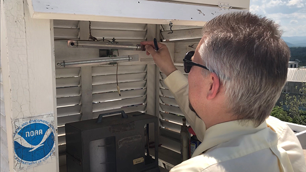 A weather observer looking into their instrumentation box