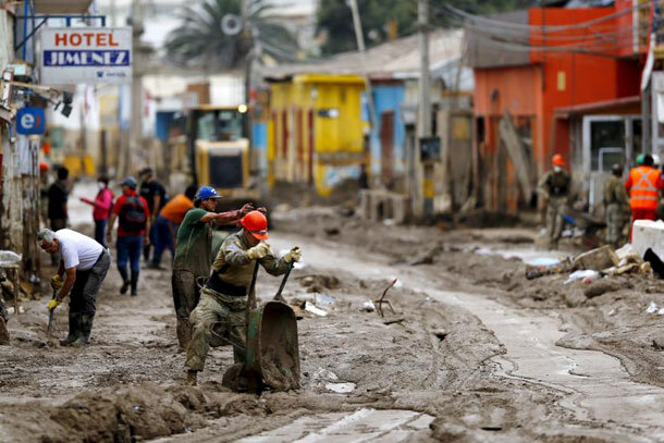 Photo depicting people removing mud from the streets after flooding at Chanaral town in Chile, on April 8, 2015