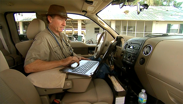 A man in a car checks a laptop