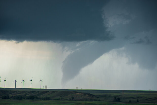 photo of a tornado near a row of wind turbines