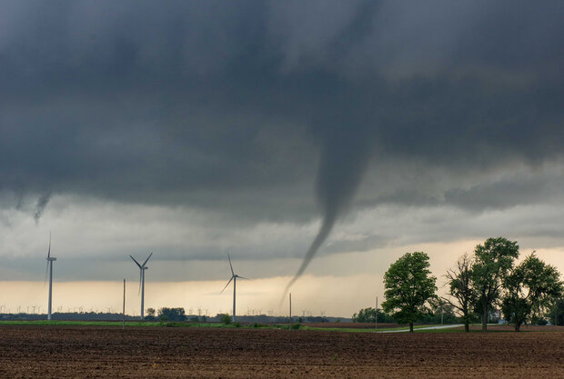 Photo of a thin tornado, wind turbines, and cropland
