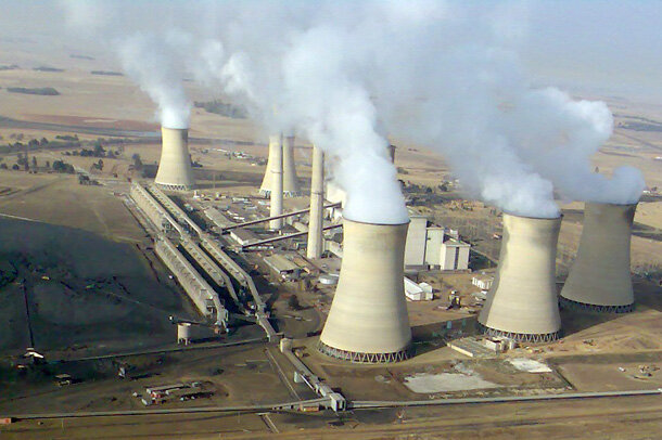 Aerial photo of coal-fired power station in South Africa showing steam and smoke coming out of several smokestacks.